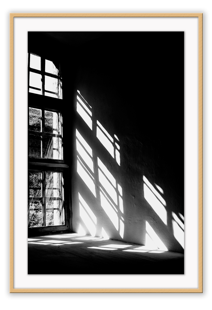 A black and white wall art with sunlight penetrating through big windows casting window shadows and creating high contrast.  