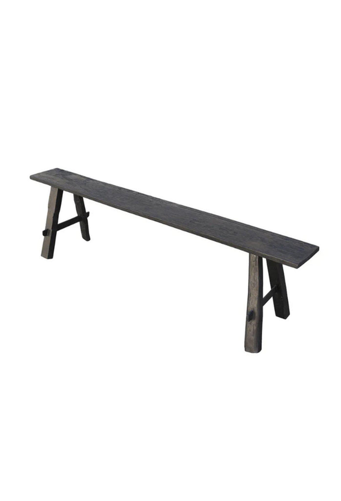 Rustic thin black wooden bench with a long rectangular seat and black wooden legs with natural imperfections
