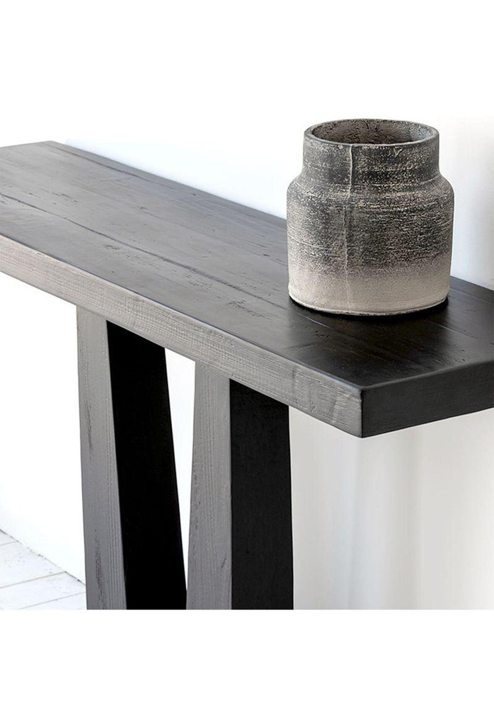 Modern black wooden console table with two chunky legs which connect to one solid base on the bottom
