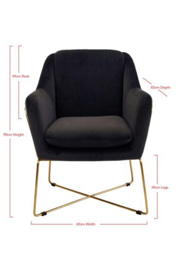 Modern armchair fully upholstered in black velvet with slim gold metal legs connecting at the bottom forming a crossed base