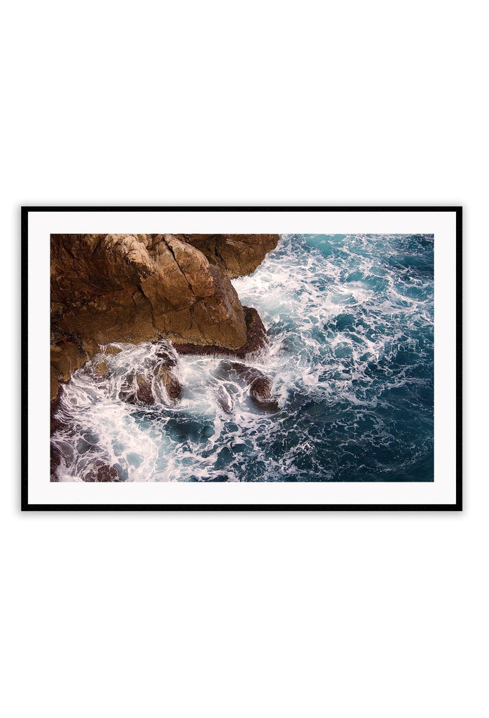 A natural wall art with a blue ocean rocks crashing waves on coastline white wash.