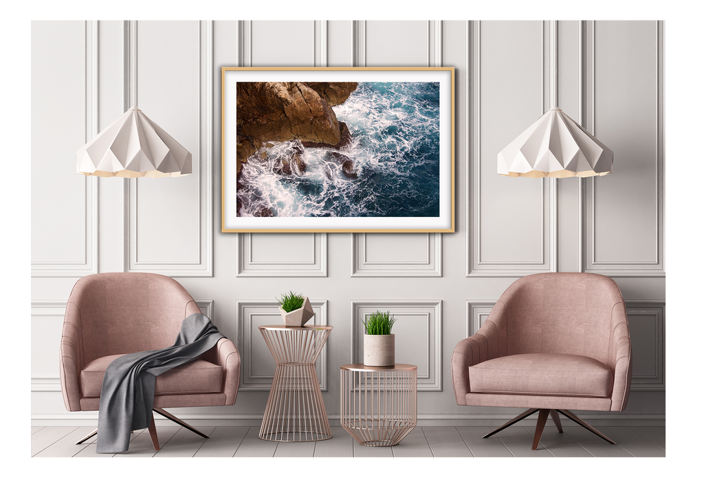 A natural wall art with a blue ocean rocks crashing waves on coastline white wash.