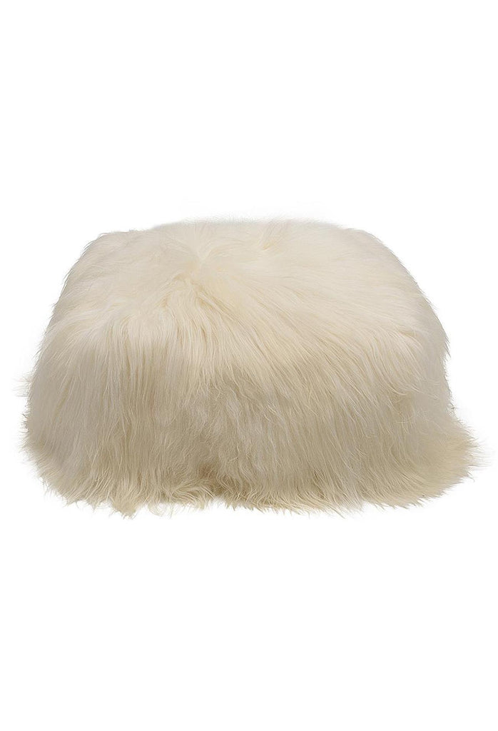 Cubic pouffe with round edges fully upholstered in natural white icelandic sheepskin on white background
