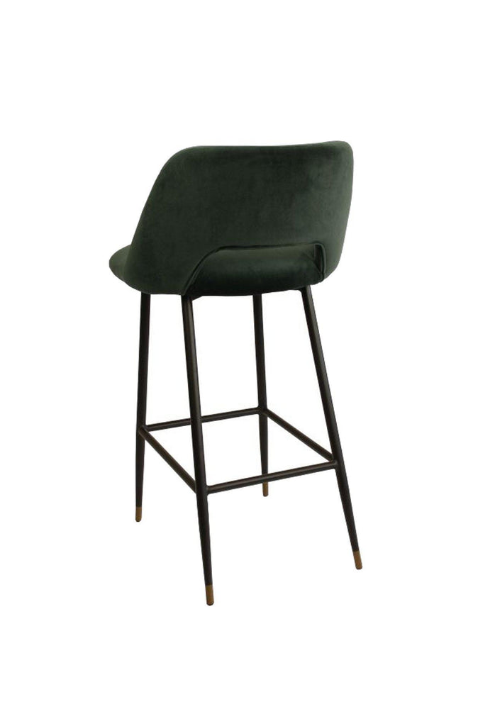 Black bar stool with seat and backrest upholstered in dark green velvet and black metal frame feauring a foot rest on a white background