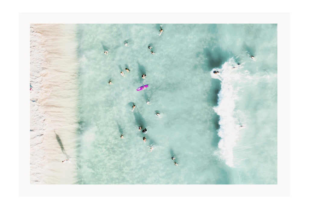 Coastal style photography beach landscape print with people swimming in blue water from a birds eye view.